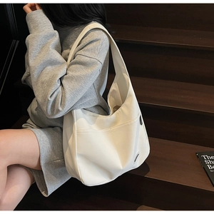 Detailed side view of a minimalist white Hobo shoulder bag with a wide strap on a model