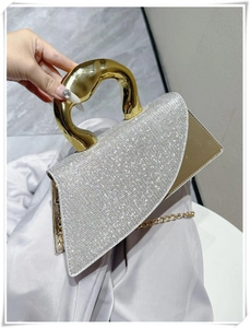 Detail of luxury rhinestone handbag with golden irregular metal handle and chain