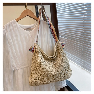 Close-up of hand-woven straw tote bag with colorful jacquard straps and hollow pattern