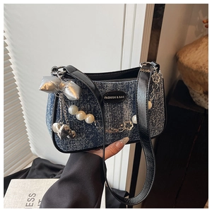 Détail du sac polochon en denim bleu avec nœud argenté, perles et chaîne fleurie