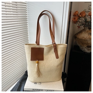 Detail of straw woven tote bag texture with brown leather strap and tassel charms