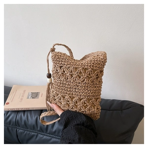 Detail of woven bucket bag featuring hollow star patterns and beaded tassel charm