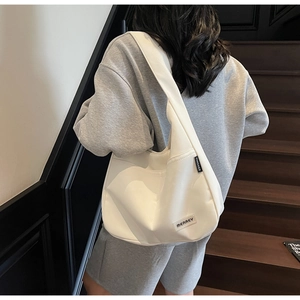 Close-up of a white minimalist hobo shoulder bag featuring a Merrey rectangular label