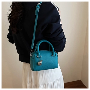 Mini sac Boston bleu paon en cuir grainé porté par un mannequin pour un look mode