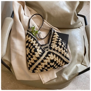 Detail shot of the woven checkerboard hobo bag featuring a black leather strap and textured fabric