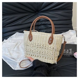 Detail of straw bucket bag with brown leather handles and adjustable shoulder strap