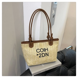 Detail of woven tote bag with COIH 2DN embroidery and dark brown leather handles