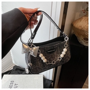Détail d'un sac sous le bras en tweed avec nœud argenté et chaîne florale perle