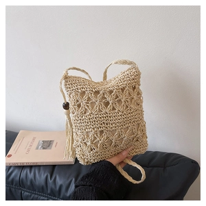 Detailed close-up of woven straw bucket bag featuring fringe tassels and wood beads