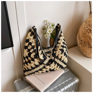 Close-up of woven checkerboard hobo bag with leather strap on luggage and daisy