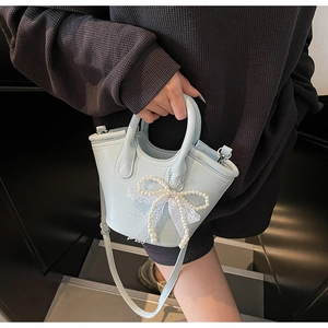 Detail of mint blue leather bucket bag featuring pearl bow charm and lace trim