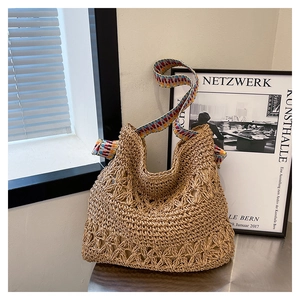 Close-up of straw woven tote with hollow crochet pattern and colorful geometric strap