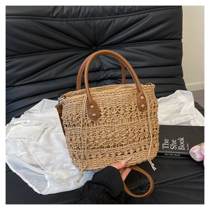 Detail of woven straw tote bag with brown leather handles and drawstring lining on sofa