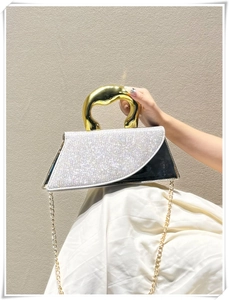 Detail of asymmetric geometric handbag with silver crystals and gold sculptural handle