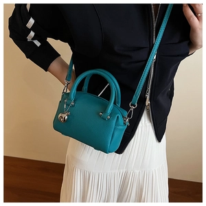 Gros plan du sac Boston turquoise avec texture à motif litchi et bandoulière amovible