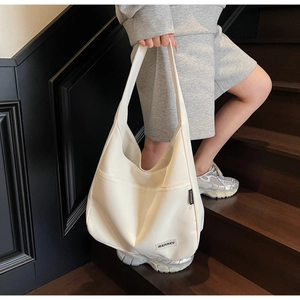 Detail of a white canvas tote bag with MERREY label shown on wooden stairs