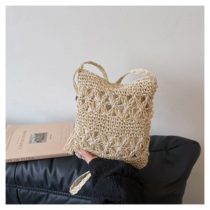 Detailed close-up of cream hand-woven bucket bag featuring tassel and hollow floral patterns