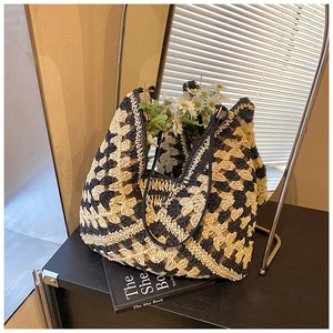Detail of checkered woven straw tote bag with black leather straps and daisy decor