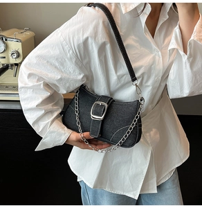 Detail of vintage denim shoulder bag with silver buckle and chain strap on a model