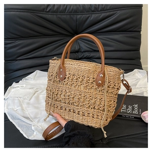 Detail of hand-woven straw tote bag with brown leather handles and adjustable strap