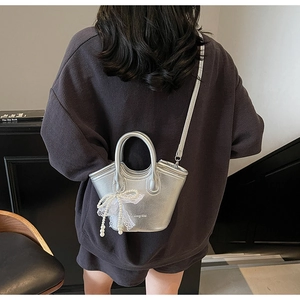 Detail of silver mini tote bag with white lace bow and pearl tassel on waffle top