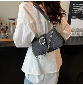 Detail of black denim shoulder bag featuring white contrast stitching and silver metal buckle