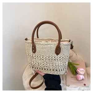 Detail view of woven straw bucket bag with brown leather handle and drawstring liner