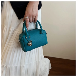 Détail du mini sac Boston bleu lac avec pendentif doré et texture cuir grainé