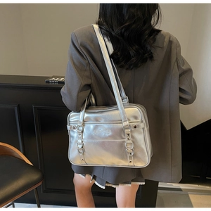 Close-up of metallic silver tote bag featuring multi-buckle straps and dual handles