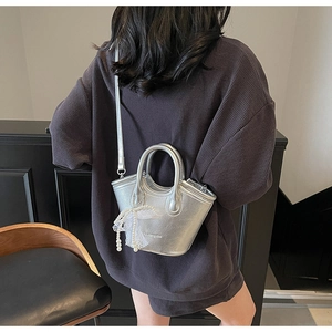 Detail of silver metallic mini bucket bag with white lace bow and pearl chain charm