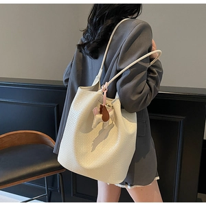 Modern white woven tote bag with a small horse charm shown on a model's shoulder