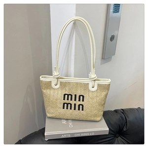 Detail of hand-woven straw tote bag with min min embroidery and cream leather handles