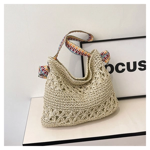 Detail of hand-woven straw tote with hollow floral patterns and colorful woven strap