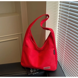 Close-up of red canvas shoulder bag with external pocket and brand logo detail