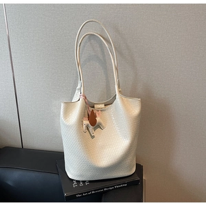 Close-up of cream woven tote bag texture with elegant pegasus charm on a book