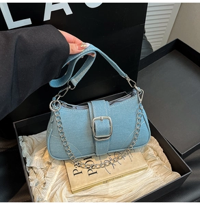 Detail of light blue denim shoulder bag with silver chain and metal buckle detail