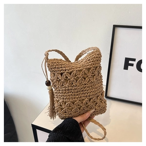 Detail of hand-woven straw bucket bag featuring hollow flower patterns and long tassels