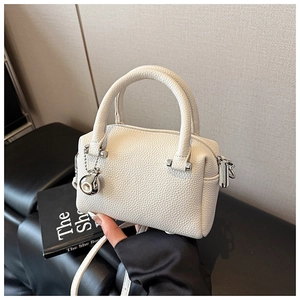 Vue détaillée du sac Boston blanc à motif litchi avec pendentif boule argenté