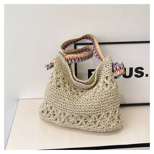 Detail of hollow-out straw tote bag featuring a colorful geometric jacquard strap