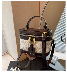 Detail of vintage brown and cream woven bucket bag with gold hardware and leather tag