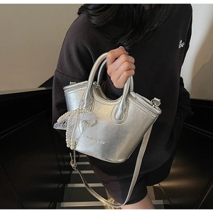 Detailed macro of silver metallic mini tote bag with pearl lace bow charm accessory