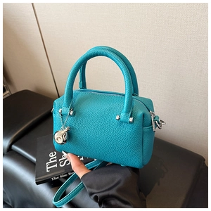 Détail du sac Boston en cuir turquoise avec pendentif sphère argentée et bandoulière