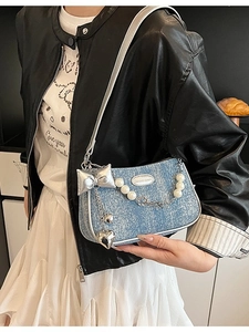 Sac à bandoulière en denim bleu clair avec chaîne de perles porté par un mannequin