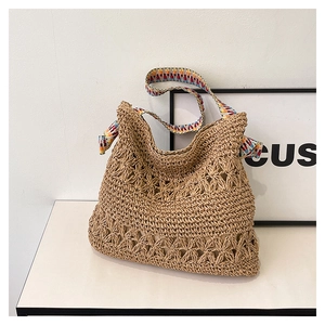 Detail of straw tote bag showing hollow-out weave and bohemian geometric strap