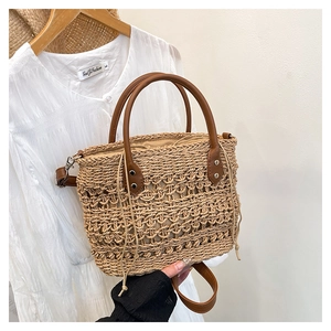 Detail of straw woven tote bag featuring brown leather handles and a drawstring liner
