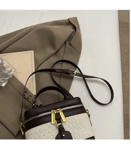 Detail of a vintage two-tone bucket bag with white woven leather and brown trim on a blazer