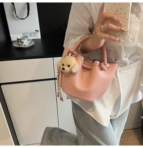 Détail du sac seau en cuir rose avec peluche de chiot et décoration en foulard de soie