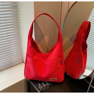 Detail of red large capacity canvas tote bag with front pocket and brand label