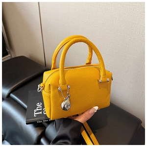 Détail du sac Boston jaune vif avec texture grainée et pendentif sphérique argenté élégant