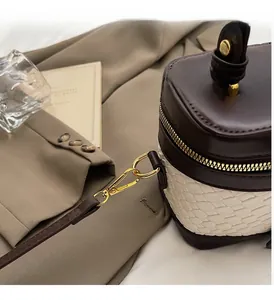 Detail of high-quality gold hardware and brown leather trim on a stylish bucket bag
